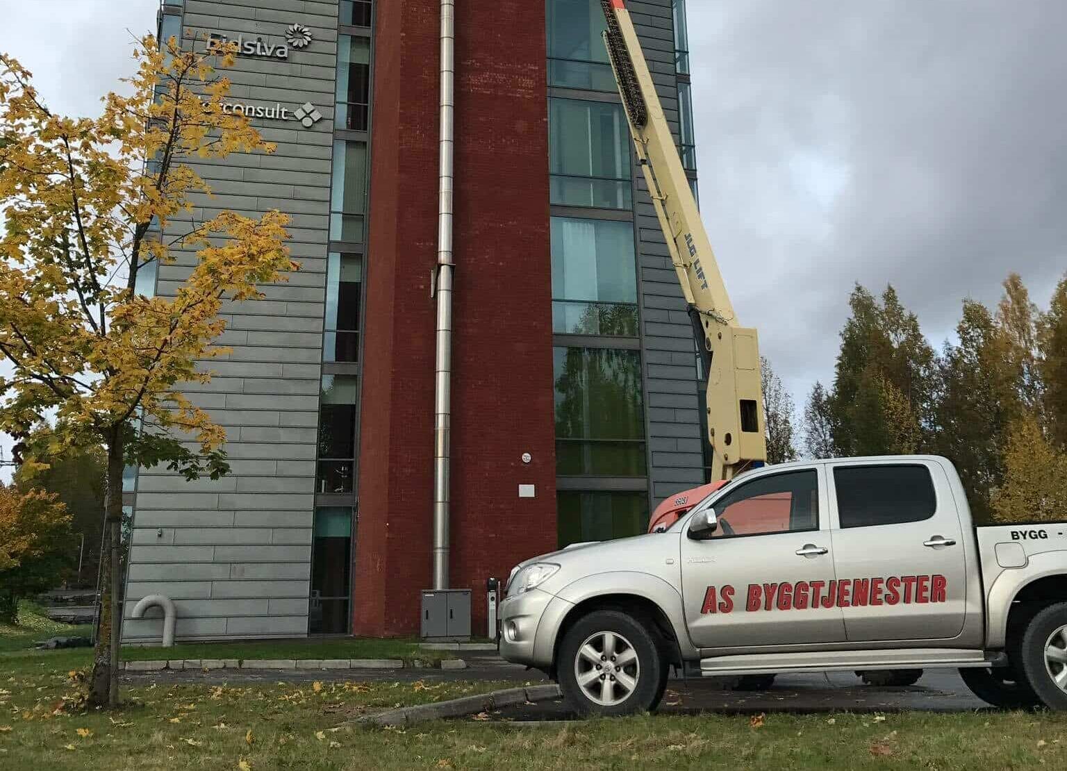 AS Byggtjenester bil foran høyt bygg